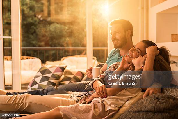 affectionate family relaxing together in the living room. - sun flare couple stock pictures, royalty-free photos & images