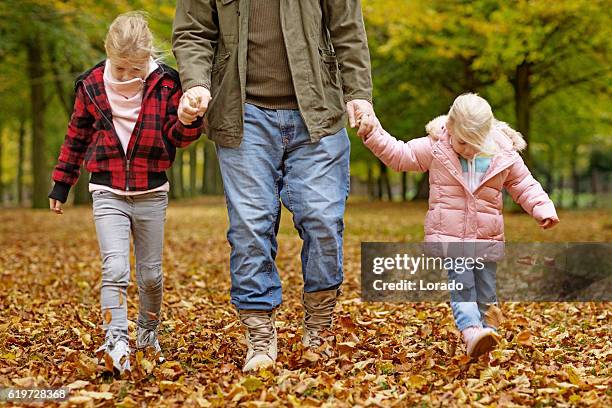 alleinerziehender vater und töchter spazieren gemeinsam im herbstlichen park - witwer stock-fotos und bilder