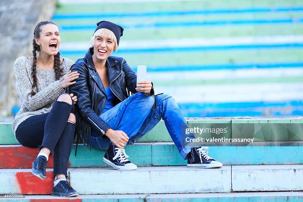 Two cheerful girls sitting on stairs