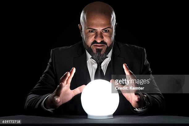 mysterious fortune teller gesturing at crystal ball - goochelaar stockfoto's en -beelden
