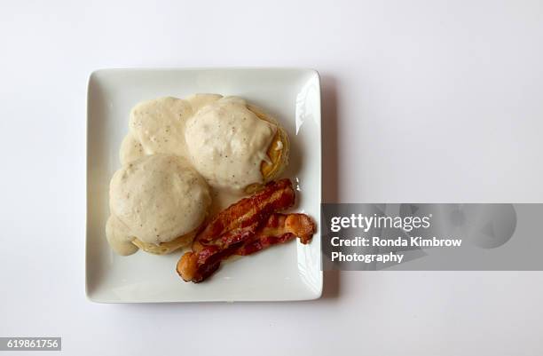 biscuits and gravy with two slices of bacon isolated on white background - biscuit au babeurre photos et images de collection