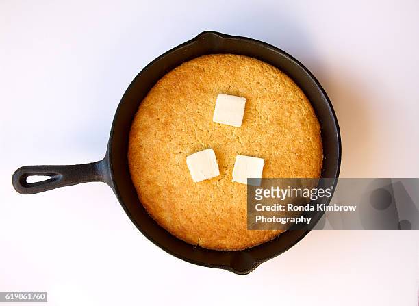 butter melting on cornbread cooked in a cast iron skillet isolated on white background - pão de milho - fotografias e filmes do acervo