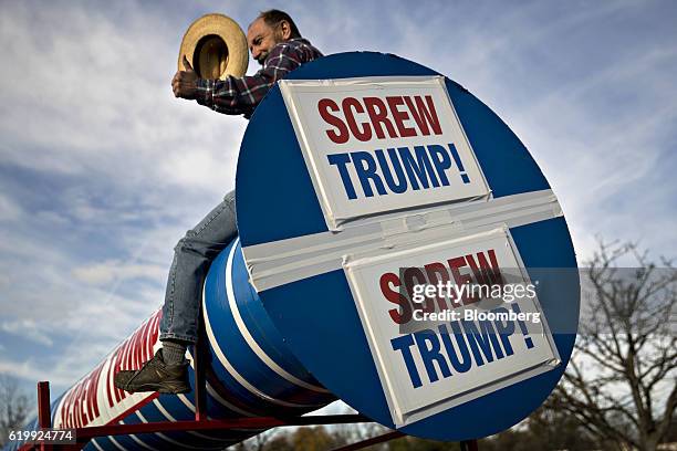 Man sits on a replica of a screw with a sign reading "Screw Trump" ahead of an address by Donald Trump, 2016 Republican presidential nominee, on...