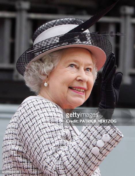 Britain's Queen Elizabeth II waves from the gangway of the British Royal Navy aircraft carrier "HMS Illustrius" in Valletta's main harbour in Malta,...