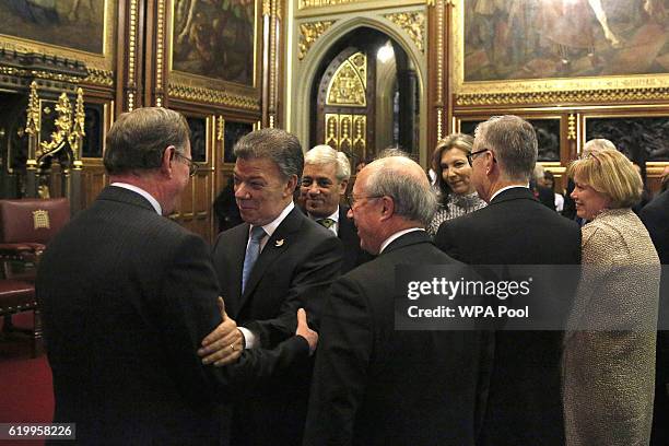 Colombia's President Juan Manuel Santos reacts as he greets fellow Nobel Peace Prize winner Lord David Trimble, following his address to members of...