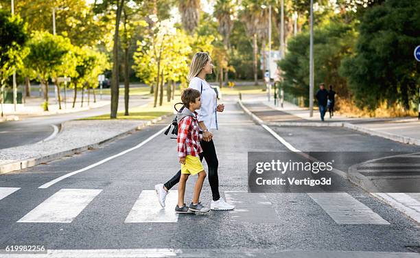 son and mom holding hands - cross road children stockfoto's en -beelden