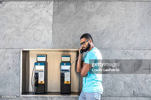 man having a call on a phone booth in downtown - telephone booth stockfoto's en -beelden