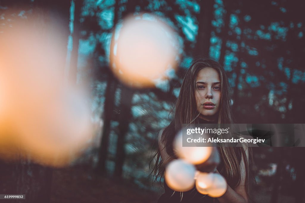 Beautiful Young Girl with Light bulbs at Night in Forest
