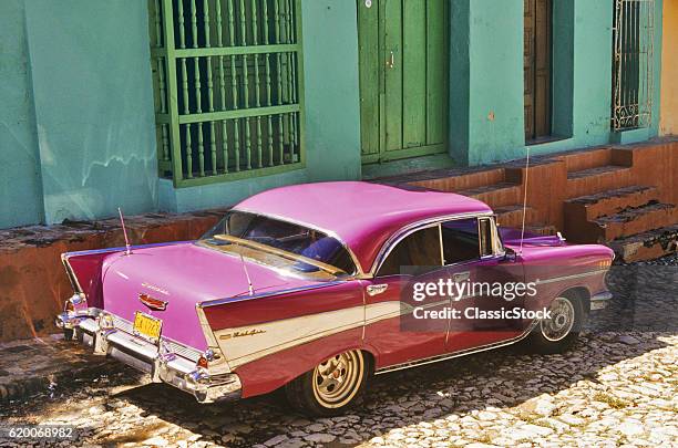 2000s VINTAGE PINK CHEVY BEL AIR CAR PARKED BY GREEN PAINTED BUILDING TRINIDAD SANCTI SPÍRITUS PROVINCE CUBA