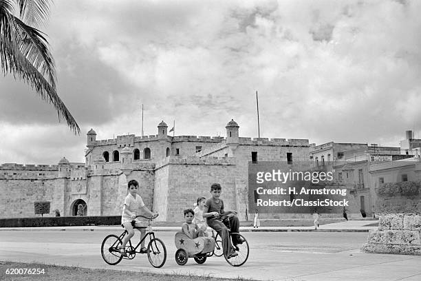 1950s FOUR CHILDREN RIDING BICYCLES ON AVIENDA DEL PUERTO HAVANA CUBA