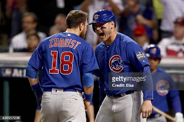 Ben Zobrist of the Chicago Cubs celebrates with teammate Anthony Rizzo after crashing into Roberto Perez of the Cleveland Indians to score a run in...