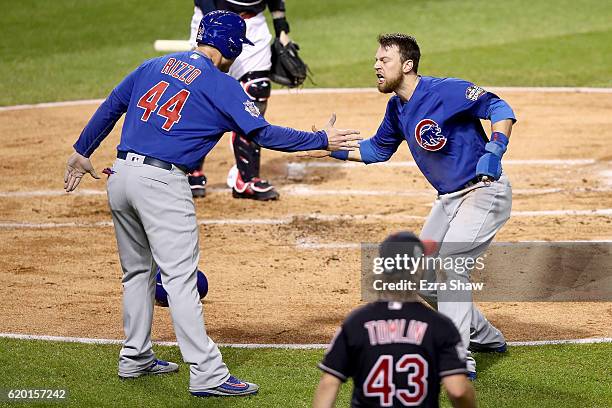 Ben Zobrist of the Chicago Cubs celebrates with teammate Anthony Rizzo after crashing into Roberto Perez of the Cleveland Indians to score a run in...