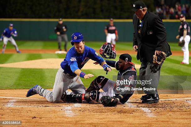 Ben Zobrist of the Chicago Cubs crashes into Roberto Perez of the Cleveland Indians to score a run in the first inning on a double hit by Addison...
