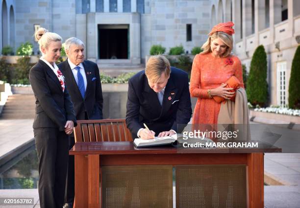 Dutch King Willem-Alexander and Queen Maxima sign the visitors book during a visit to the Australian War Memorial in Canberra on November 2, 2016....
