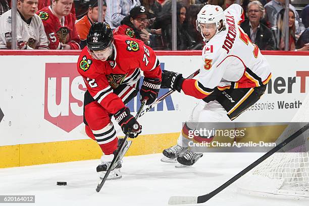 Artemi Panarin of the Chicago Blackhawks and Jyrki Jokipakka of the Calgary Flames chase the puck in the second period at the United Center on...