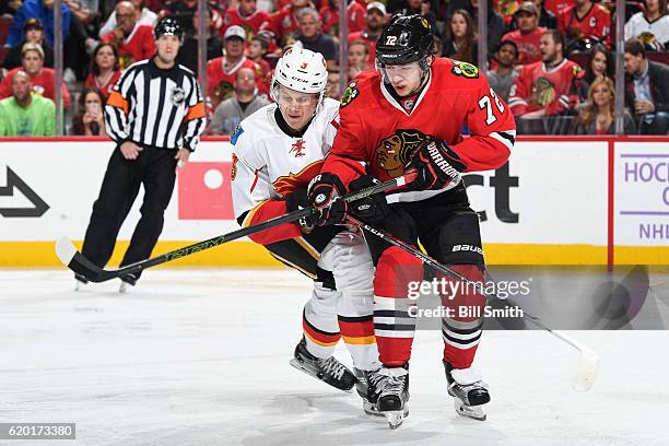 Jyrki Jokipakka of the Calgary Flames and Artemi Panarin of the Chicago Blackhawks get physical in the third period at the United Center on November...