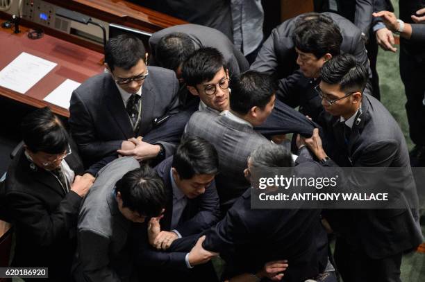 Newly elected lawmaker Baggio Leung is restrained by security after attempting to read out his Legislative Council oath at Legco in Hong Kong on...