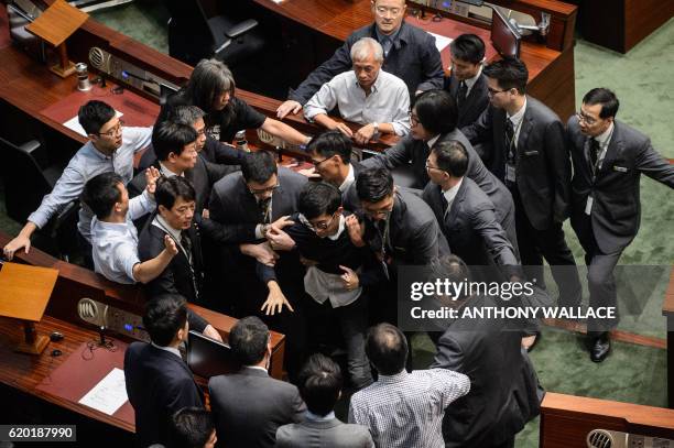 Newly elected lawmaker Baggio Leung is restrained by security after attempting to read out his Legislative Council oath at Legco in Hong Kong on...