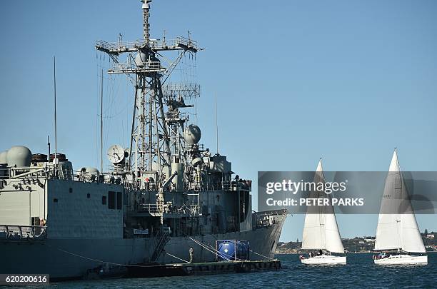 Two yachts sail past the Royal Australian Navy's HMAS Newcastle , an Adelaide-class guided missile frigate, in Sydney Harbour on November 2, 2016. /...