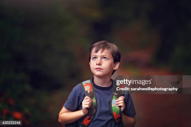 young boy walking home with backpack after school - boy brown hair stock pictures, royalty-free photos & images