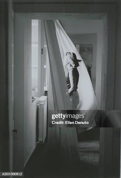 woman standing at window - curtain blowing stock pictures, royalty-free photos & images