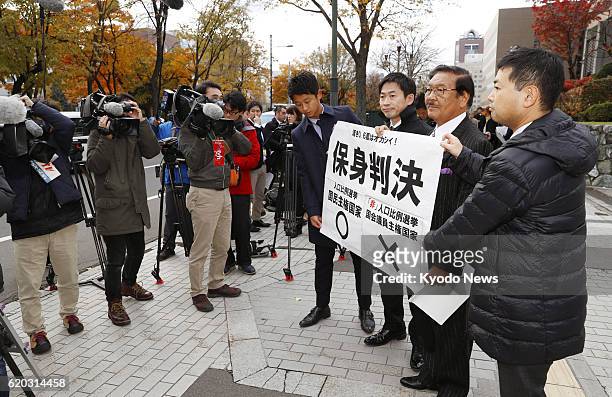 Plaintiffs' lawyers hold a banner outside the Sapporo High Court with a message criticizing a ruling by the court in northern Japan on Nov. 2 after...