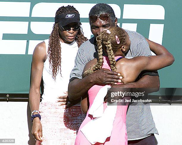 Serena Williams of the USA hugs her father Richard as her sister Venus waits in the back after her victory over Kim Clijsters of Belgium during the...