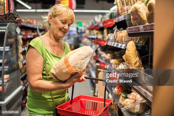 happy mature woman shopping for bread in a store. - supermarket bread stockfoto's en -beelden