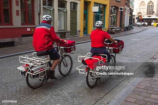 belgian postmen on bcycle at street of brugge belgium - postbode stockfoto's en -beelden