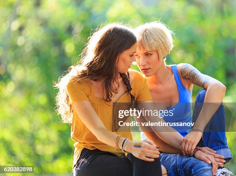 Friends sitting in park and looking at each other Friends sitting in park and looking at each other