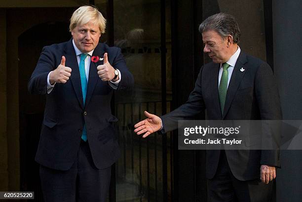 British Foreign Secretary Boris Johnson gives a thumbs up as Colombian President Juan Manuel Santos attempts to shake his hand as they visit the...
