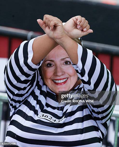 Woman dressed as Democratic presidential nominee Hillary Clinton in a prison outfit lifts her hands at a Trump rally in Miami, Florida on November 2,...