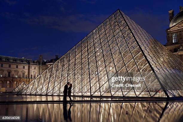 Couple kissing in front of Louvre Pyramid and the Louvre museum by night on November 02 2016 in Paris, France. The city of Paris remains the top...