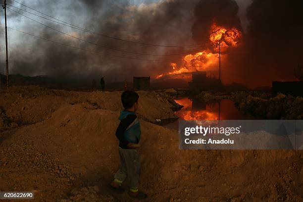 Boy looks on as fire fighters try to extinguish the fire at oil wells, were set on fire by Daesh terrorists as they fled after Al Qayyarah town's...