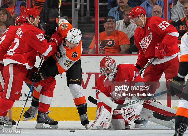 Jonathan Ericsson and Alexey Marchenko of the Detroit Red Wings protect goaltender Petr Mrazek against Brayden Schenn of the Philadelphia Flyers on...