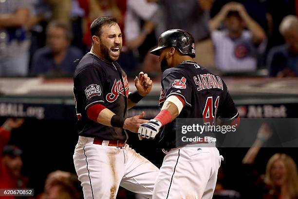 Jason Kipnis and Carlos Santana of the Cleveland Indians celebrate after scoring runs on a wild pitch thrown by Jon Lester of the Chicago Cubs during...