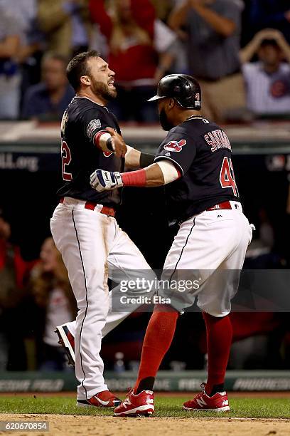 Jason Kipnis and Carlos Santana of the Cleveland Indians celebrate after scoring runs on a wild pitch thrown by Jon Lester of the Chicago Cubs during...