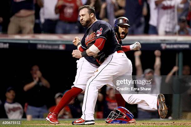 Jason Kipnis and Carlos Santana of the Cleveland Indians celebrate after scoring runs on a wild pitch thrown by Jon Lester of the Chicago Cubs during...