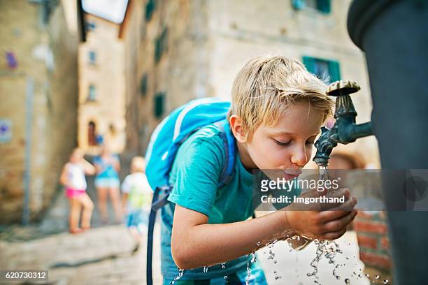wenig touristisches trinkwasser aus dem öffentlichen brunnen - kind wasser stock-fotos und bilder