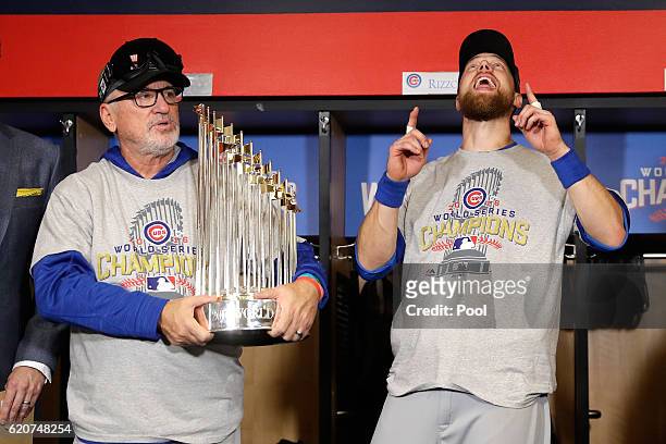 Manager Joe Maddon of the Chicago Cubs poses with The Commissioner's Trophy as Ben Zobrist reacts after the Chicago Cubs defeated the Cleveland...