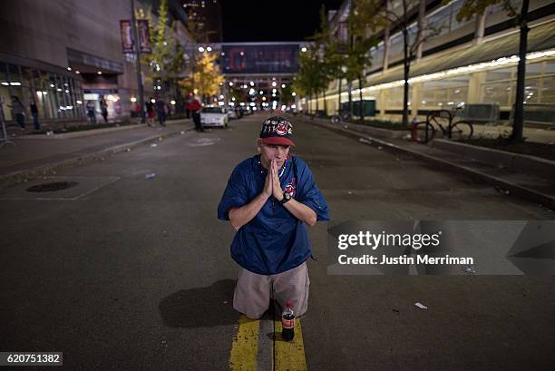 William Burgos of Cleveland prays in the street outside of Progressive Field during the 9th inning of game 7 of the World Series between the...