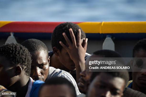 Migrants and refugees sit aboard the Topaz Responder ship run by Maltese NGO Moas and the Italian Red Cross during a rescue operation on November 3...