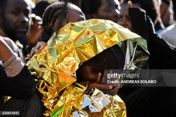 Woman wrapped in a survival foil blanket holds her head aboard the Topaz Responder ship run by Maltese NGO Moas and the Italian Red Cross during a...