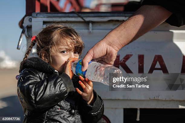 Father give water to his child as civilians fleeing neighbourhoods in Eastern Mosul that have been re-taken by Iraqi forces wait at a checkpoint...