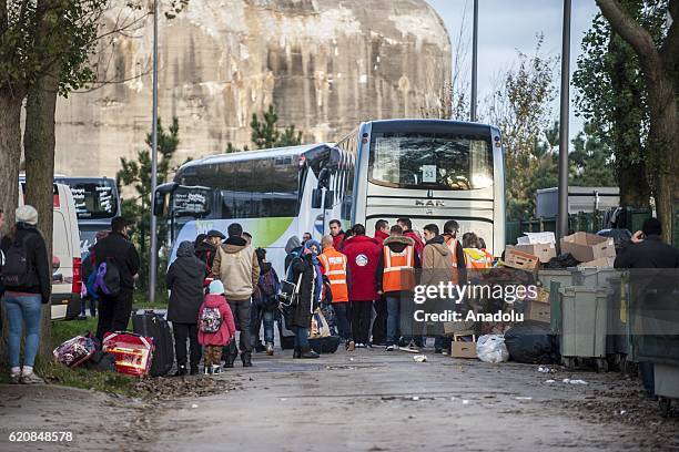 Refugees wait with their luggages as they walk to climb into a bus after leaving the "Jules Ferry" center reception, in Calais, on November 3, 2016....