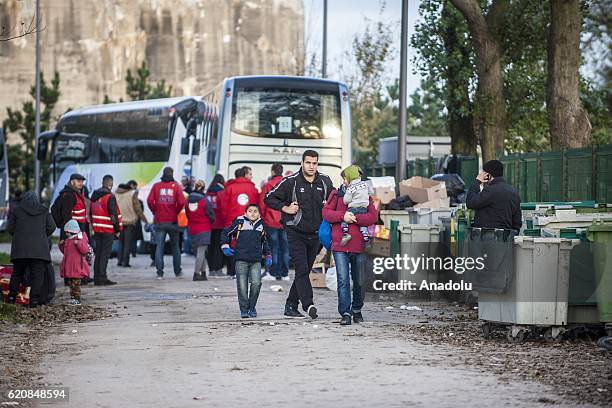 Family of refugees carry their luggages as they walk to climb into a bus after leaving the "Jules Ferry" center reception, in Calais, on November 3,...