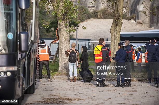 Refugees carry their luggages as they walk to climb into a bus after leaving the "Jules Ferry" center reception, in Calais, on November 3, 2016. Over...