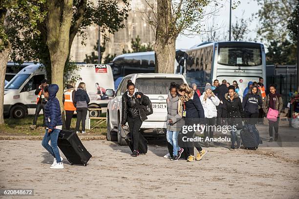 Refugees carry their luggages as they walk to climb into a bus after leaving the "Jules Ferry" center reception, in Calais, on November 3, 2016. Over...