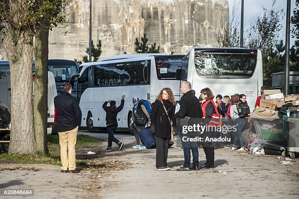 Refugees carry their luggages as they walk to climb into a bus after leaving the "Jules Ferry" center reception, in Calais, on November 3, 2016. Over...