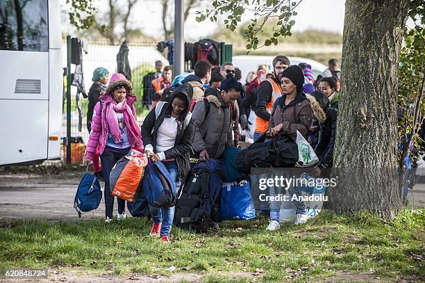 Refugees women, surrounded by the staff of the association "La Vie Active" and police, carry their luggages as they walk to climb into a bus...